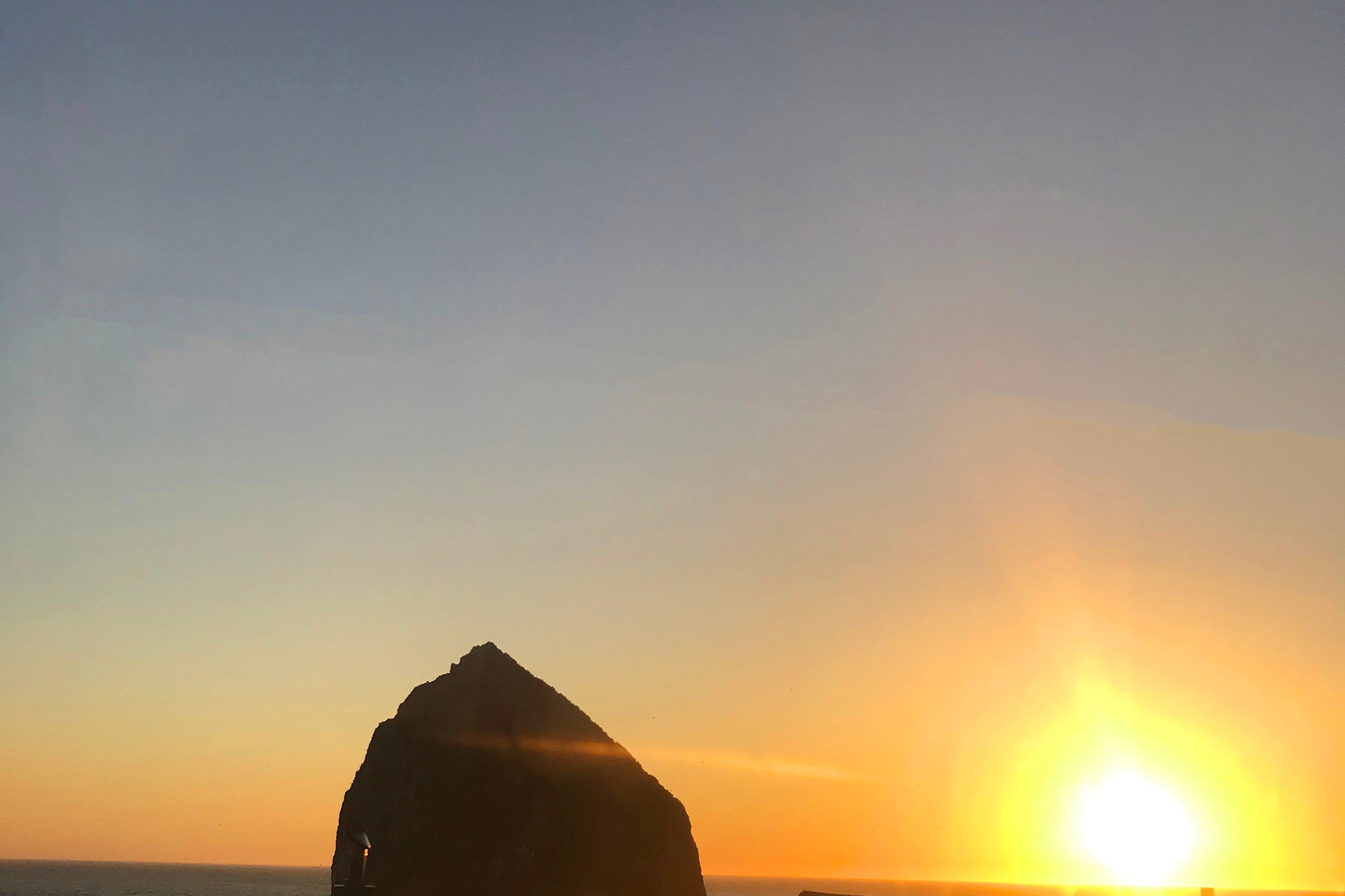 Sunset over a rocky outcrop with a rainbow halo effect.